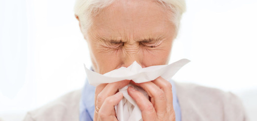 sick senior woman blowing nose to paper napkin